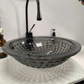 Smoked black glass vessel bowl sink above counter showing center drain opening and no overflow