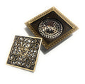 Antique brass square drain cover installed flush in tile shower floor, brass grate close-up